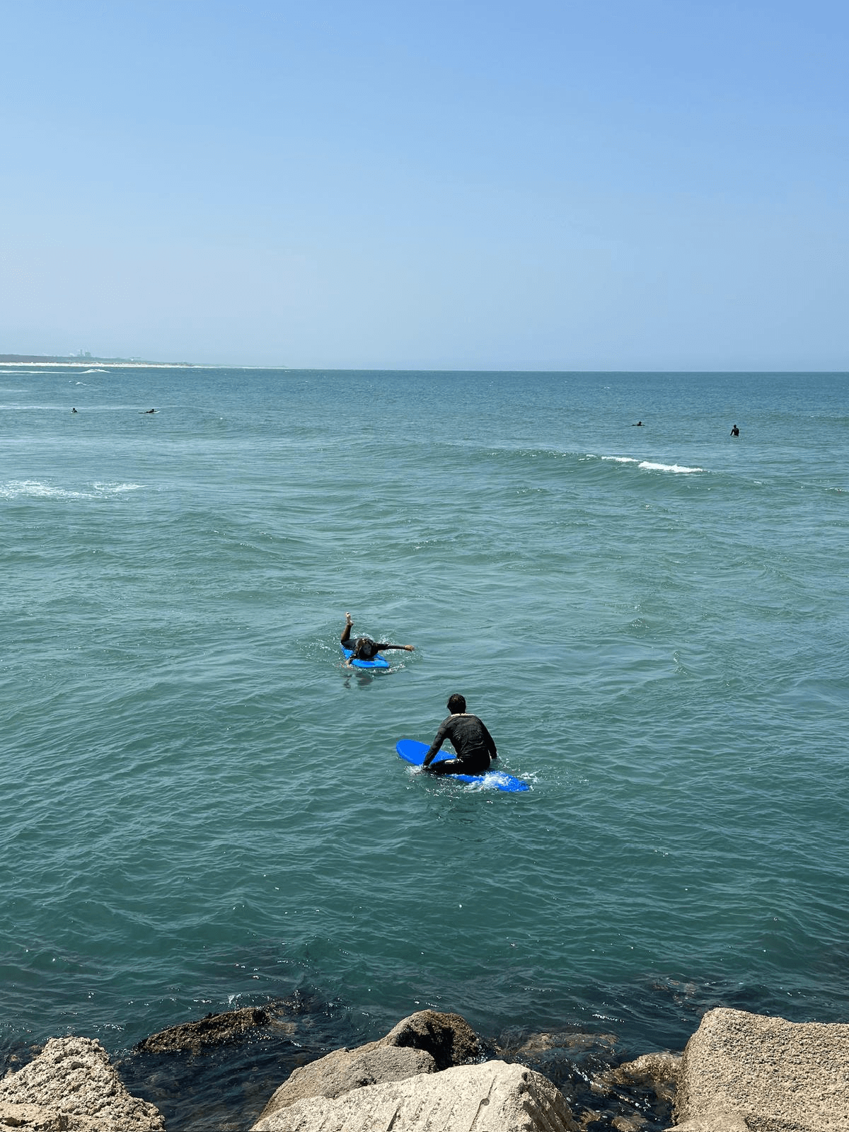 Alunos de surf a caminhar com as pranchas em direção ao mar num dia de sol
