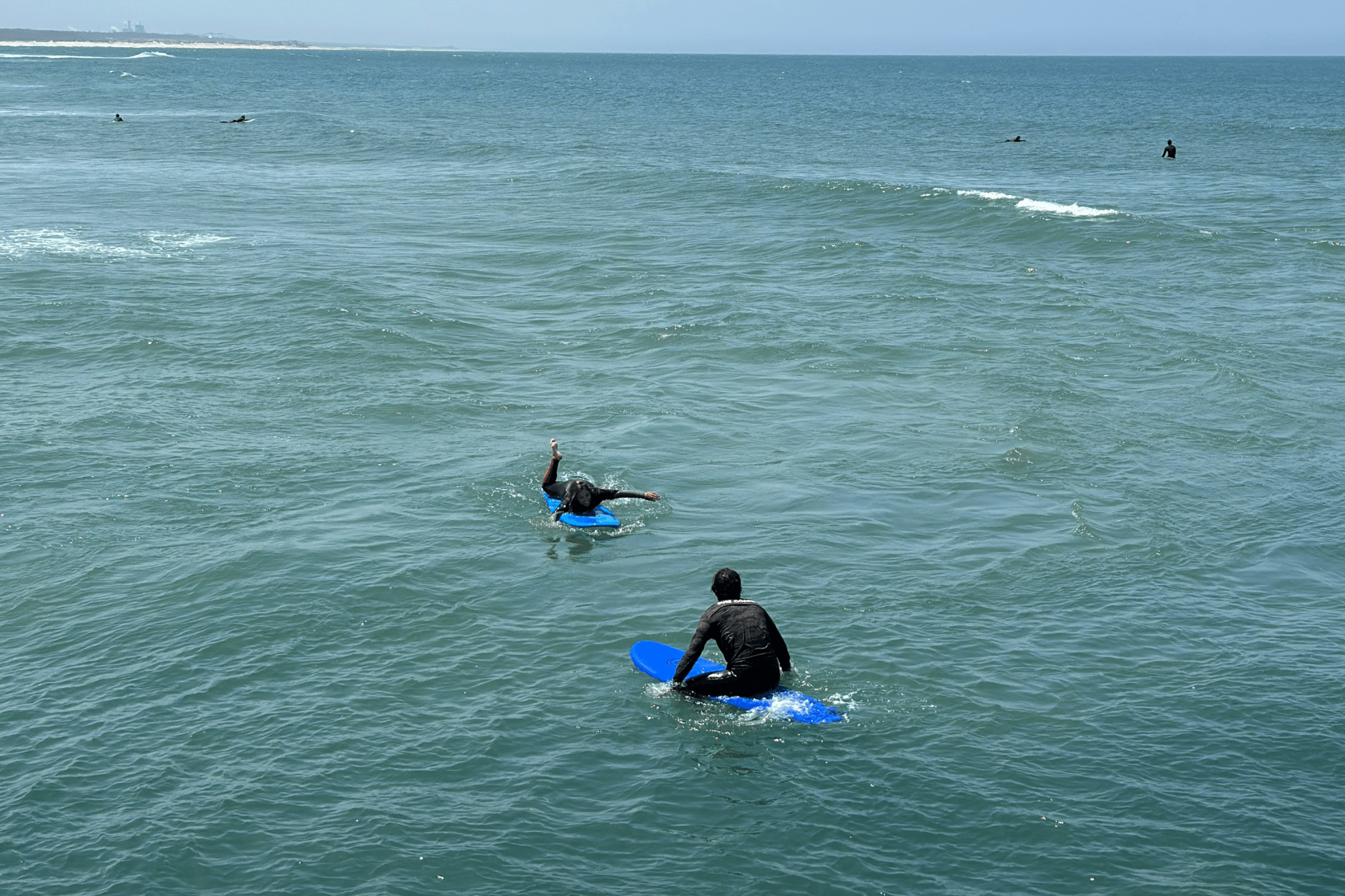 Grupo de iniciantes a fazer aquecimento na praia antes da aula de surf, em Portugal