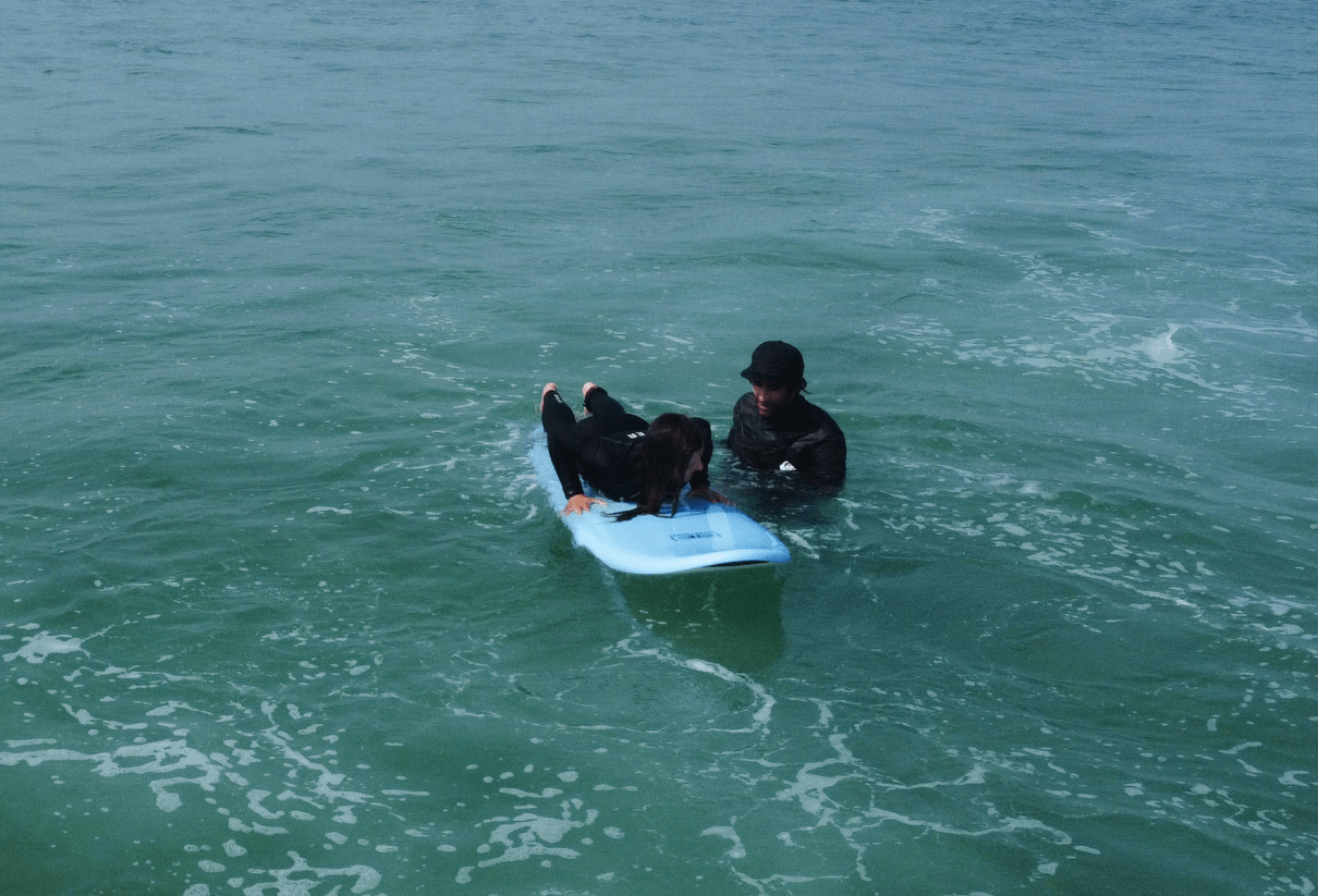 Grupo de surfistas principiantes a aquecer na praia antes da aula em Portugal